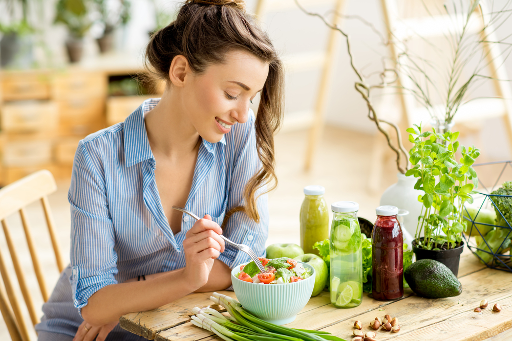 a healthy woman smiling and eating a salad