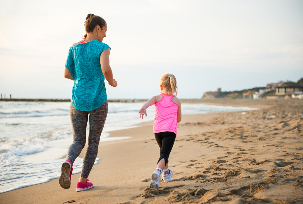 a woman running on the beach with her daughter