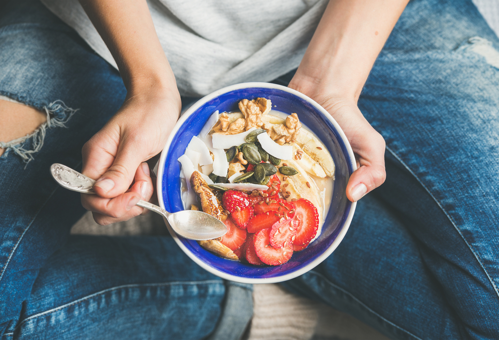 woman eating bowl of healthy foods