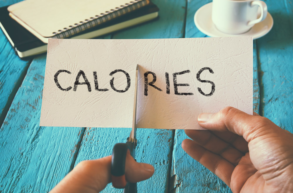 hand holding card with the word calories being cut by a pair of scissors