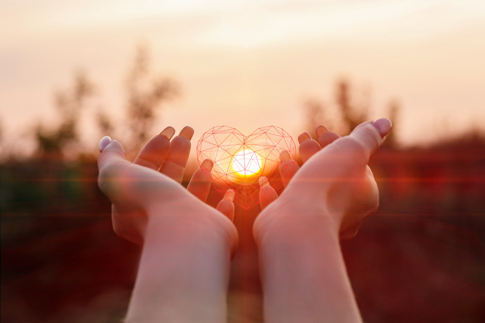 Hand holding figure of a heart up towards the sun