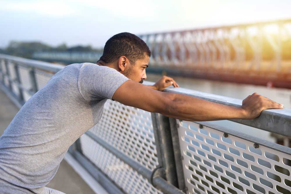 Man taking a break during run. looking over bridge. health and fitness concept.