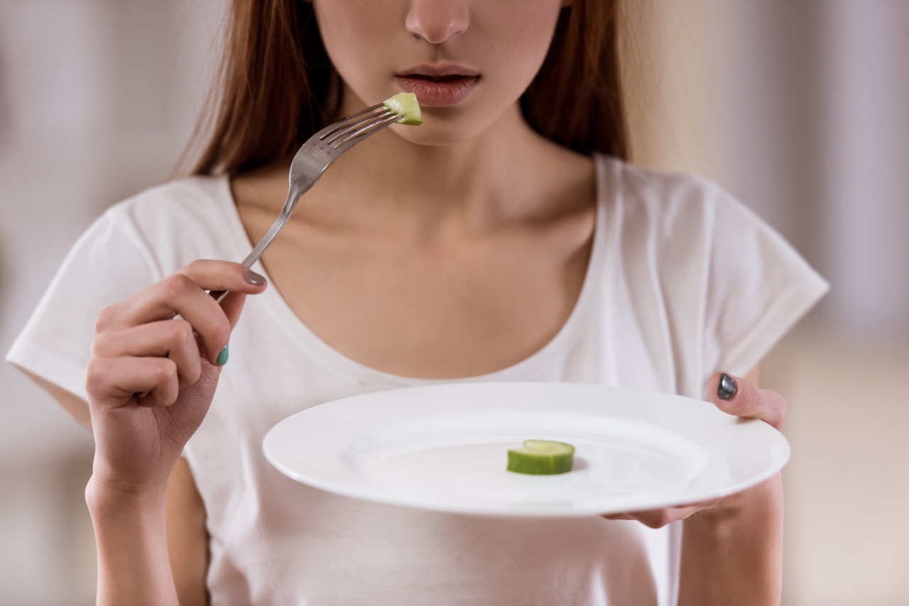 woman with eating disorder eats single cucumber slice