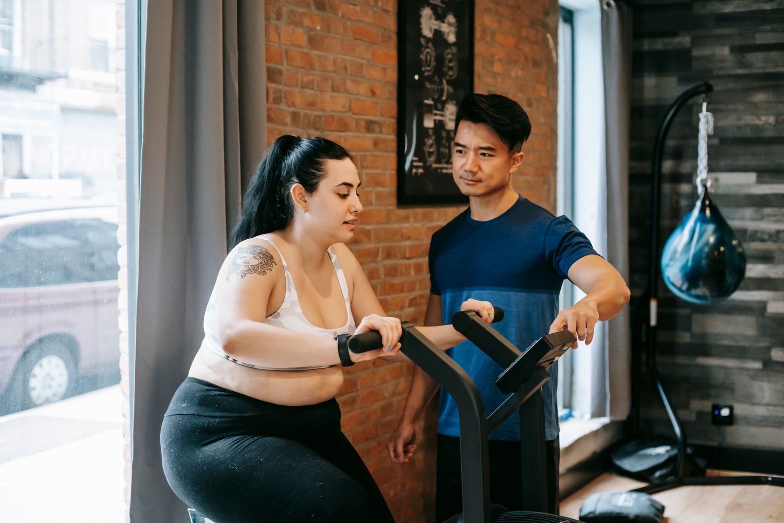 Personal trainer coaching a client through a machine exercise in a calm, uncrowded gym studio with natural light